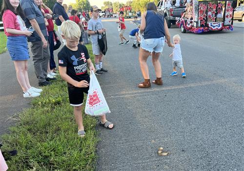 kid picking up candy thrown from homecoming floats